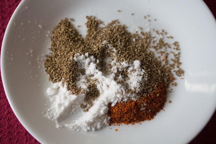 semillas de carambola, chile rojo en polvo y sal en un pequeño plato blanco