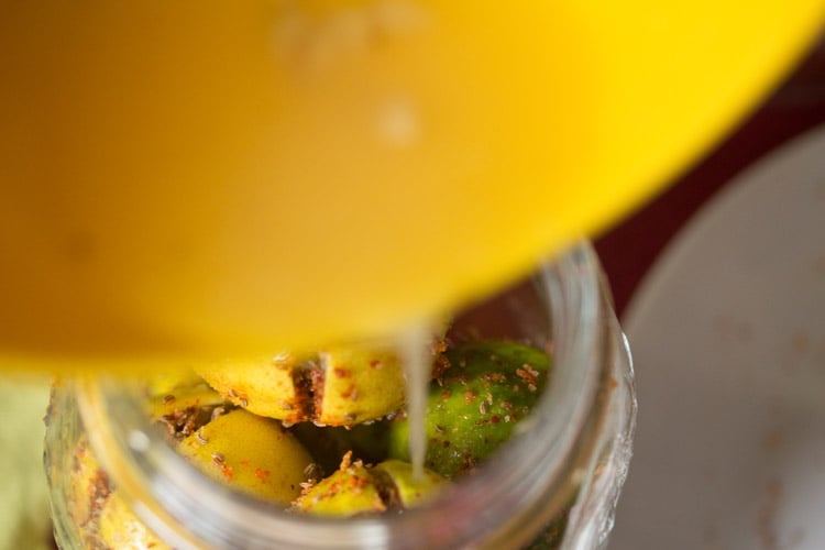 lemon juice being poured in the glass jar