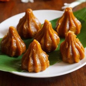 mango modaks placed over a turmeric leaf kept on a plate.