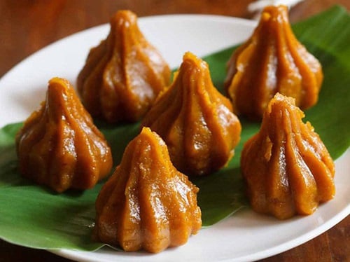 mango modaks placed over a turmeric leaf kept on a plate.