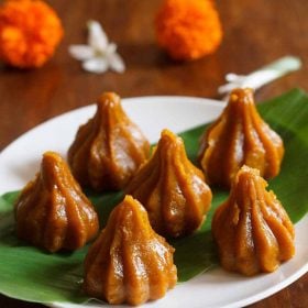 mango modak placed over turmeric leaf kept on a white plate.