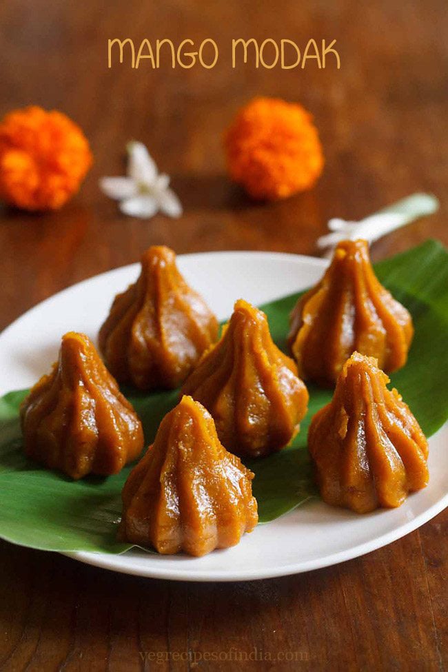 mango modak placed over turmeric leaf kept on a white plate.