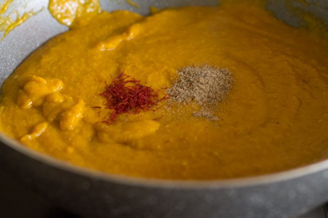 saffron strands and cardamom powder added in the mango-khoya mixture in the pan. 