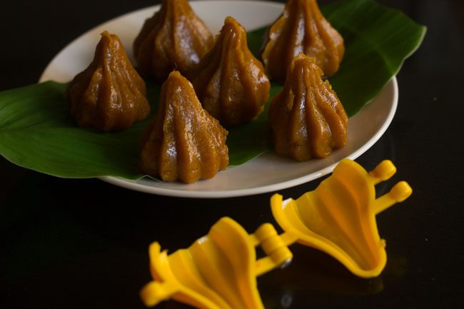 prepared mango modaks placed over a turmeric leaf on a plate. 