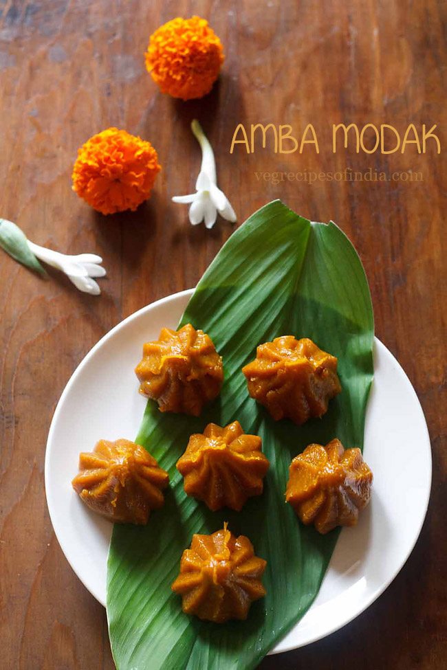 mango modaks placed over a turmeric leaf kept on a plate. 