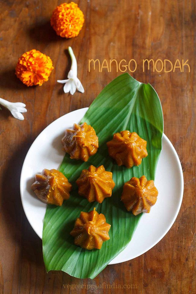 mango modaks placed over a turmeric leaf kept on a plate. 