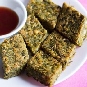 kothimbir vadi served on a white plate with a small bowl of chutney on the side.