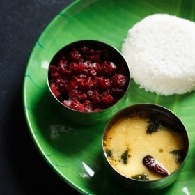 majjige saaru served in a bowl placed on a green plate with steamed rice and beetroot poriyal and text layover.