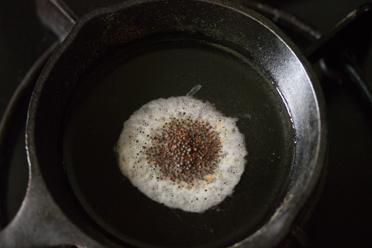 mustard seeds added to hot oil in pan. 