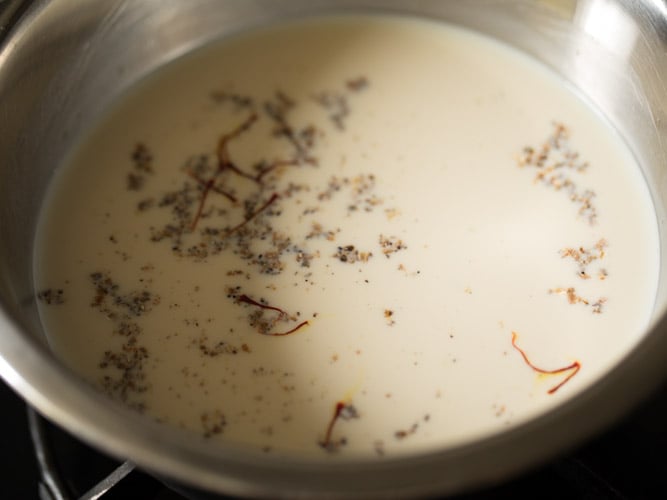 cardamom powder and saffron strands added to condensed milk mixture and heating it to warm. 