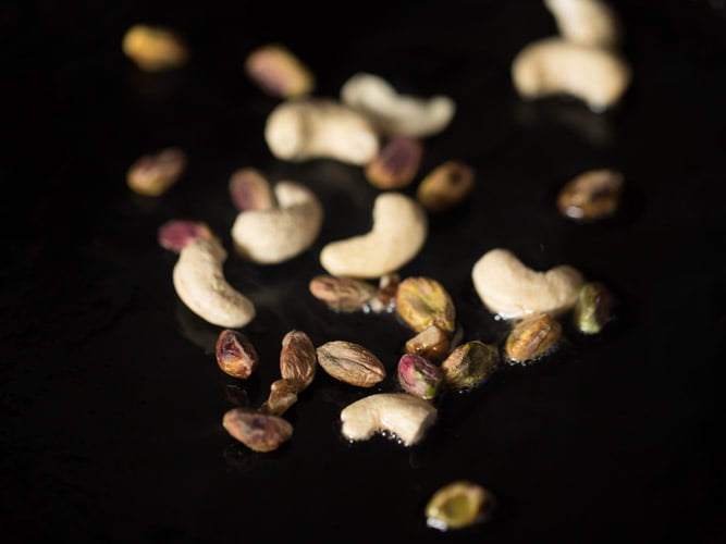 cashews and pistachios added to hot ghee in pan. 