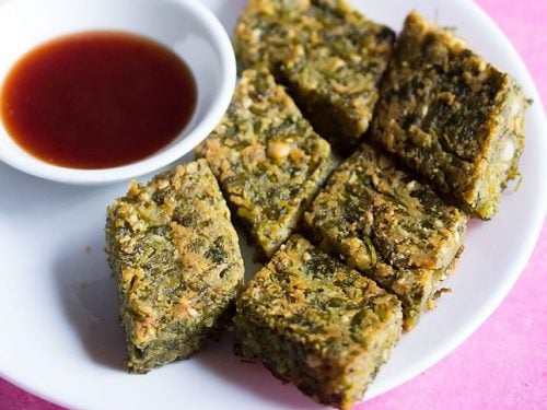 kothimbir vadi served on a white plate with a small bowl of chutney on the side.