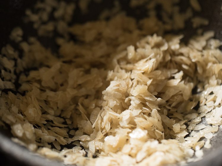 mixing poha with ghee for aval payasam recipe. 