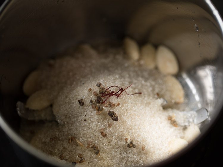 sugar, saffron, and cardamom added to grinder jar with badam.