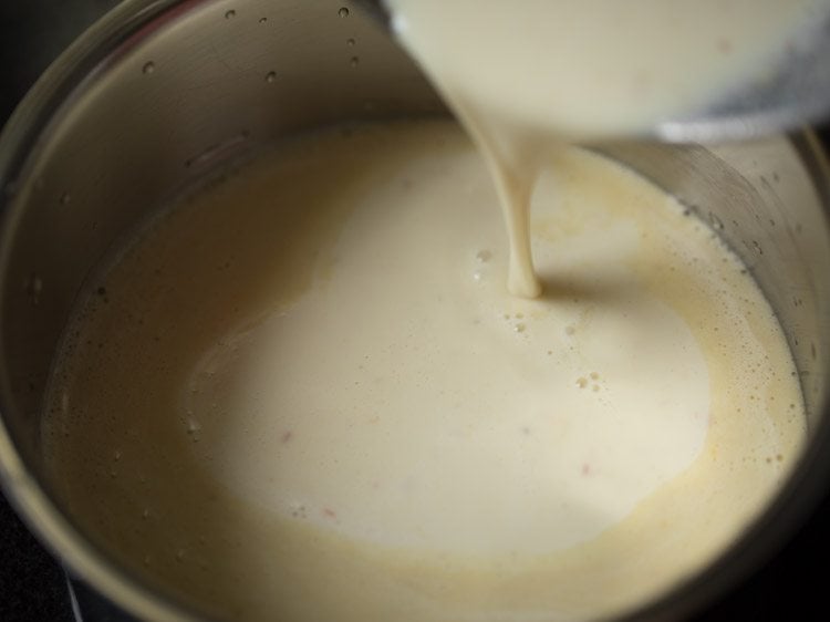 pouring the badam milk into a saucepan to warm.