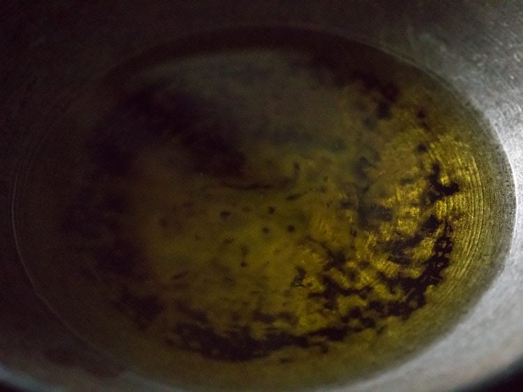 heating ghee in a heavy kadai for frying besan for besan barfi recipe. 