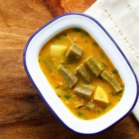 bhindi ka salan served in a blue-rimmed white bowl with text layover.