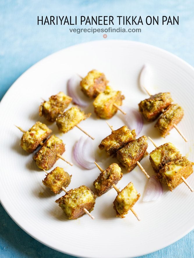 hariyali paneer tikka served on a white plate with onion slices and text layovers. 