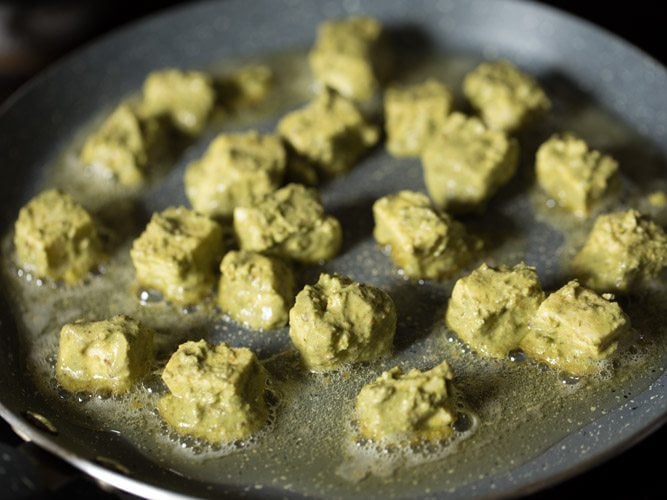 pan frying marinated paneer cubes in hot oil on tawa. 