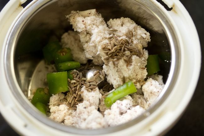 tightly packed fresh grated coconut, chopped green chilies and cumin seeds added to grinder jar for making coconut paste for kalan recipe.