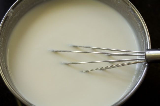 beating sour curd with a wired whisk for kalan recipe.