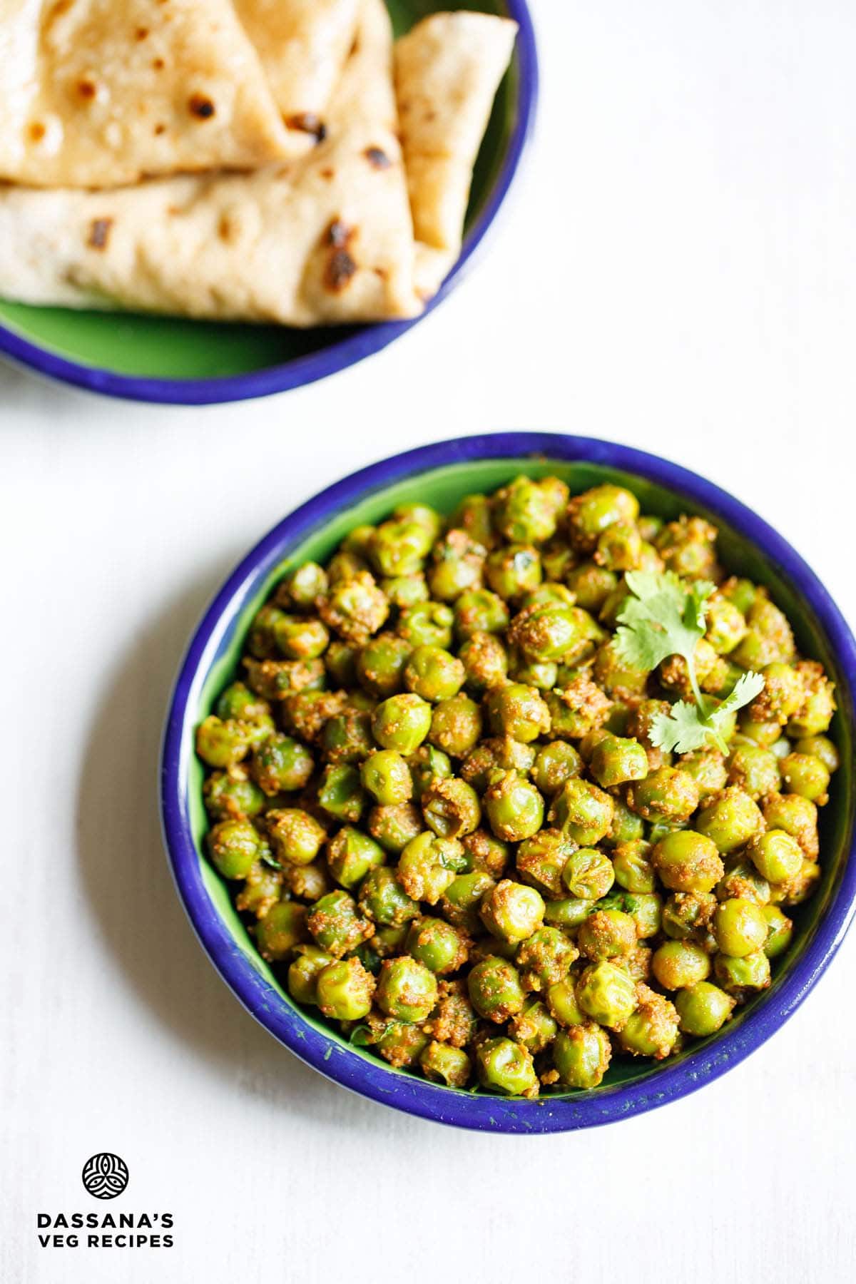 Matar sabzi in blue rimmed green bowl with folded chapatis placed at top.