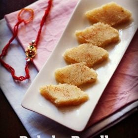 coconut burfi on a white platter with red rakhi at the side.