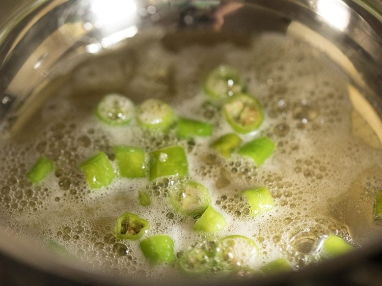 sautéing green chilies in peanut oil in pan for rishi panchami bhaji. 