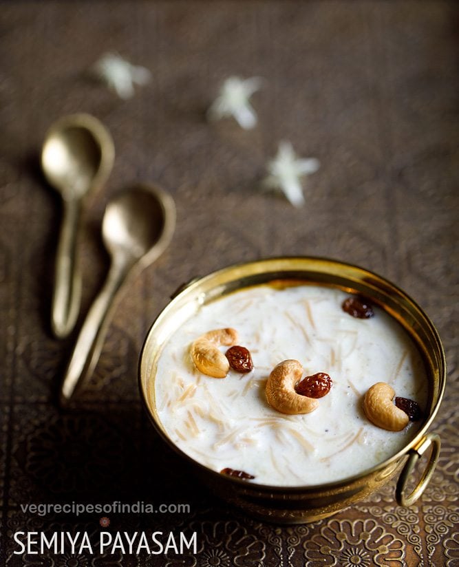 semiya payasam garnished with cashews and raisins in a brass bowl on a brass tray with small brass spoons and white flower on the tray