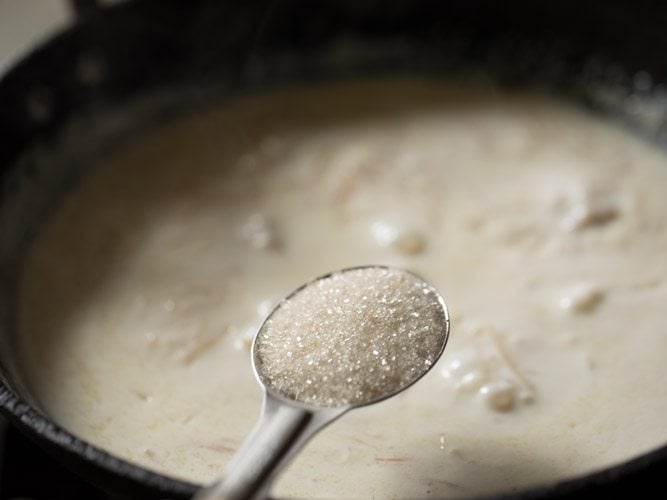 sugar being added to semiya payasam with a steel measuring spoon