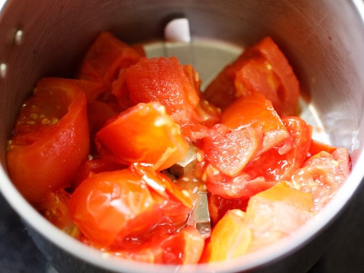 cooked tomatoes added to a grinder jar. 