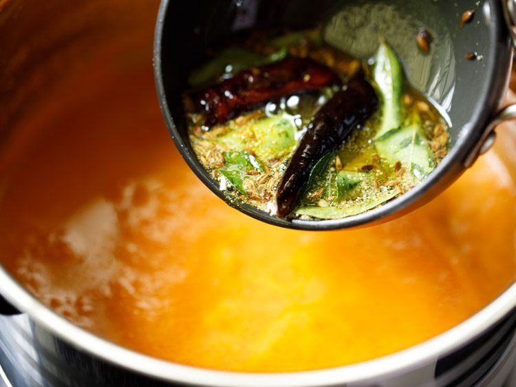 pouring the prepared tempering in the tomato saar. 