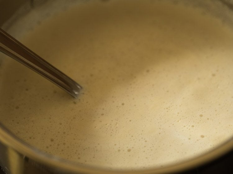 mixing almond mixture in the milk with a spoon.