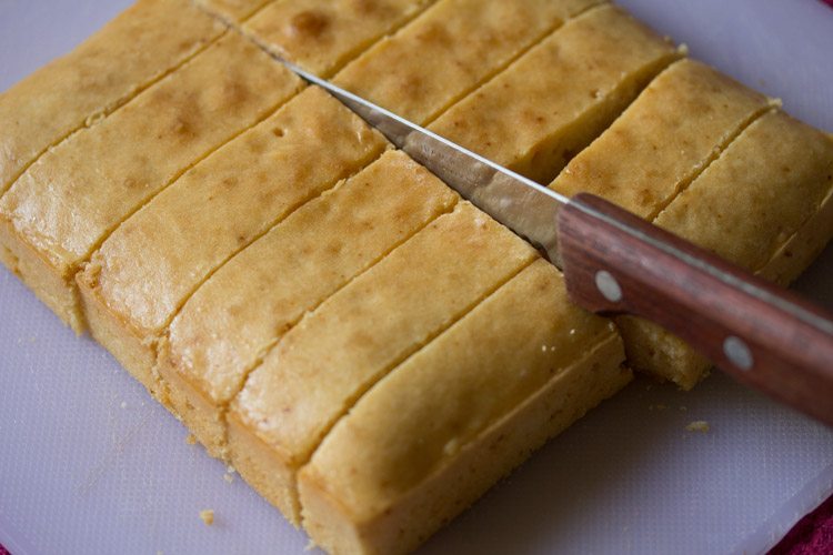 knife cutting down the middle to make 12 sponge fingers for tiramisu