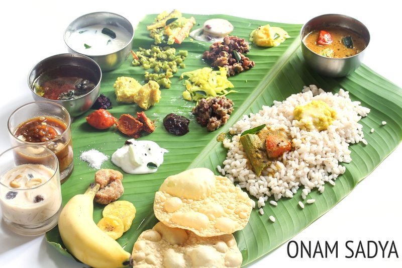 onam sadhya served on a banana leaf with text layover.