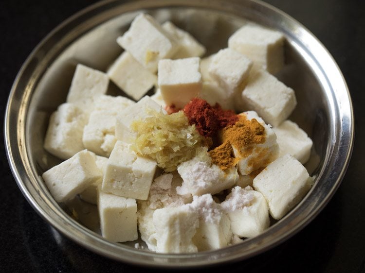 ginger-garlic paste, turmeric powder, kashmiri red chili powder and salt added to paneer cubes. 