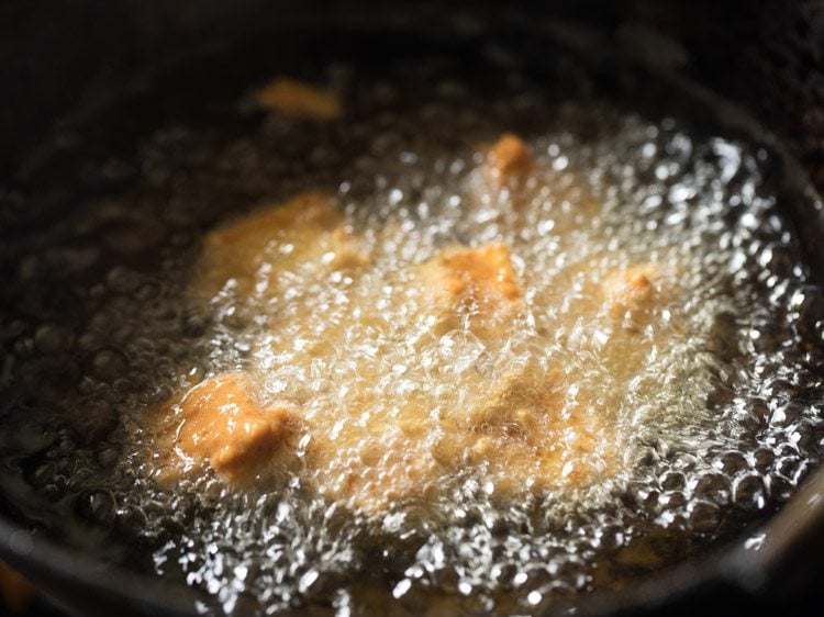 batter coated paneer cubes added to hot oil. 