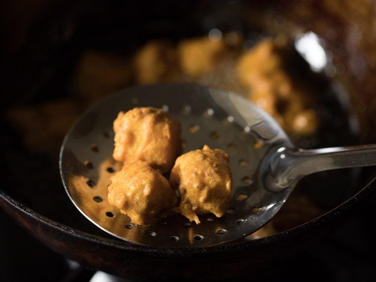 removing paneer koliwada with a slotted spoon. 