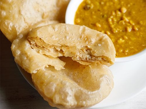 radhaballavi on a plate with cholar dal in a bowl.