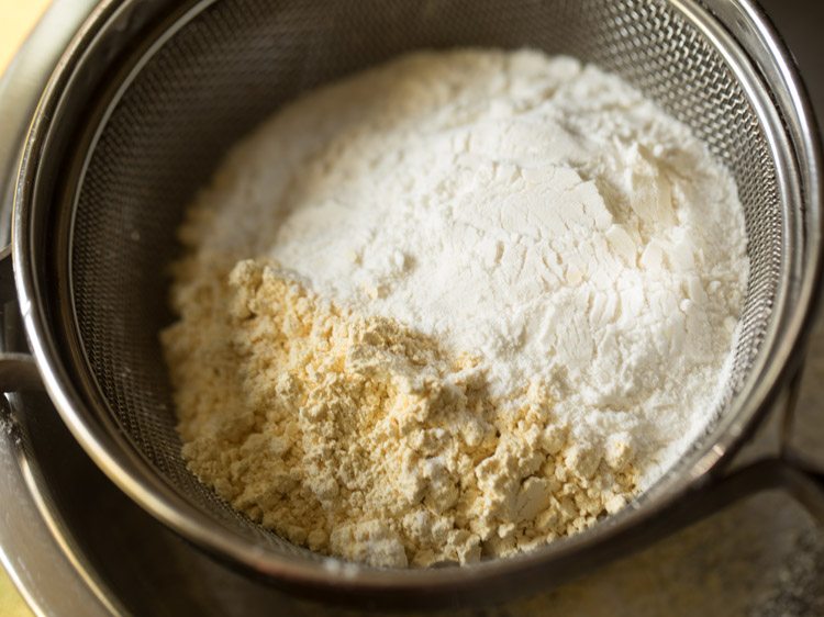 gram flour and rice flour added in a sieve placed on top of a large mixing bowl for ribbon pakoda recipe. 