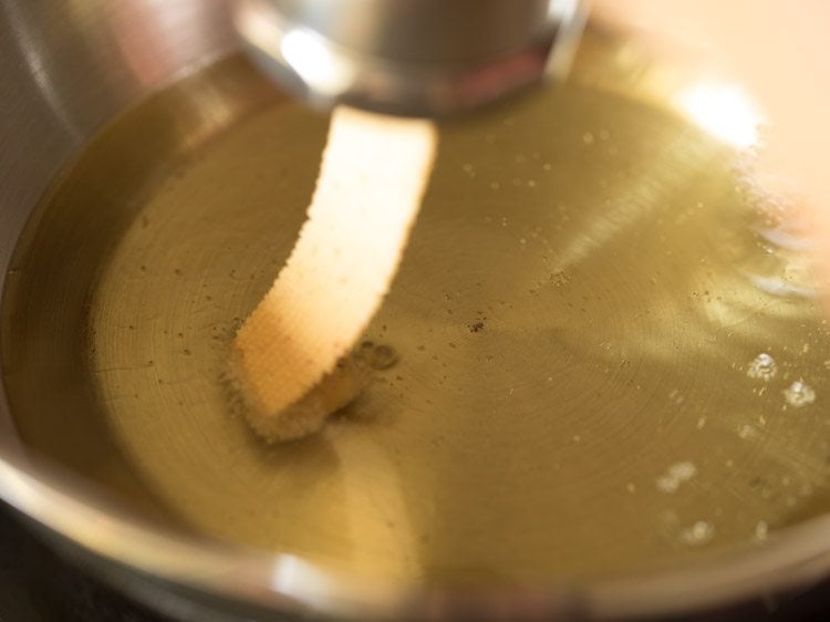 pressing the murukku maker directly into the hot oil to fry ribbon murukku. 