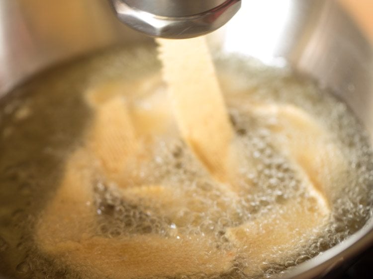 pressing murukku maker to let ribbon murukkus drop in hot oil and frying them. 