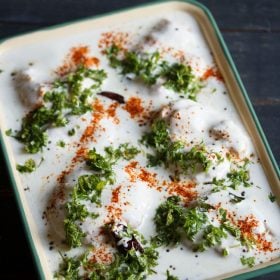 thayir vadai served in a green rimmed ceramic tray with text layovers.