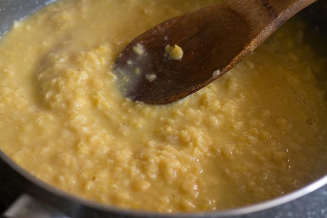 mashing cooked chana dal with a spoon.