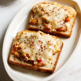 paneer toast served on a white platter with a small bowl of tomato ketchup kept on the top left side and text layovers.