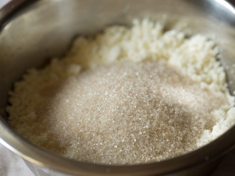 sugar added to crumbled chenna in bowl for making chenna poda. 