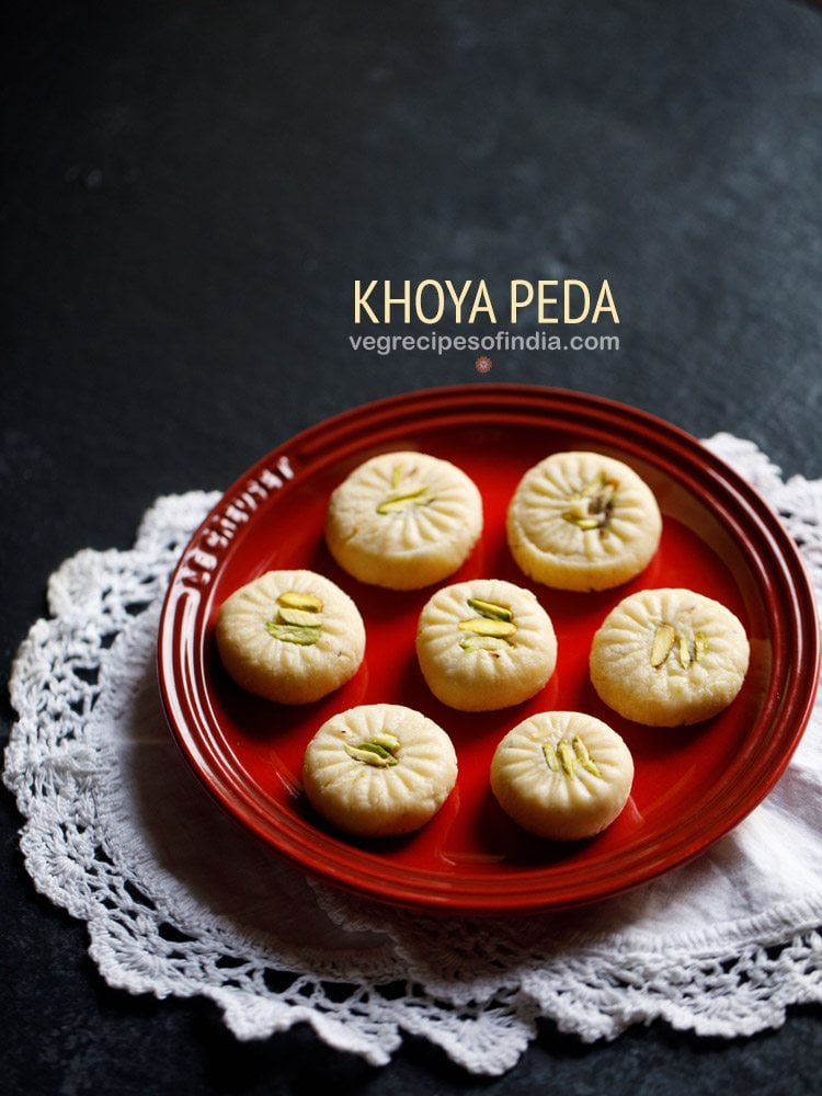 7 peda pieces on a red plate placed on white doilies.