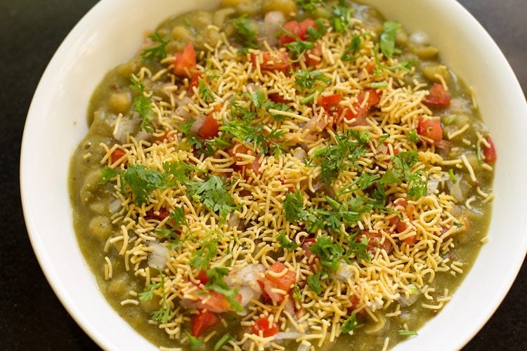 coriander leaves added and assembled masala puri in a white bowl