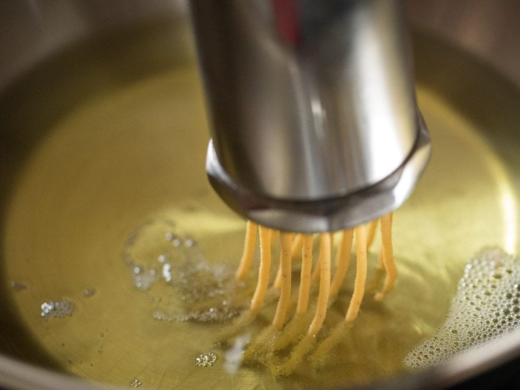 pressing sev maker directly into the oil to fry omapodi. 