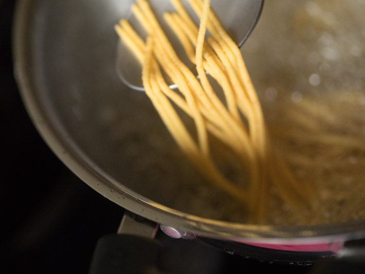 breaking top strands of sev with a spoon. 